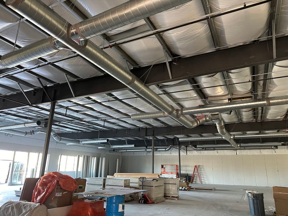 Industrial interior of a construction site with exposed ductwork and construction materials.
