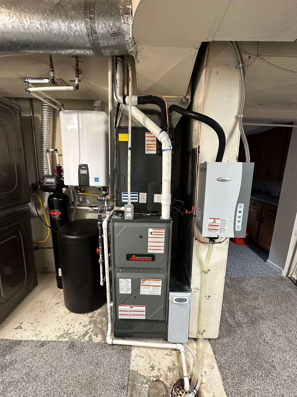 Furnace and water heater in basement with plumbing and heating system components.
