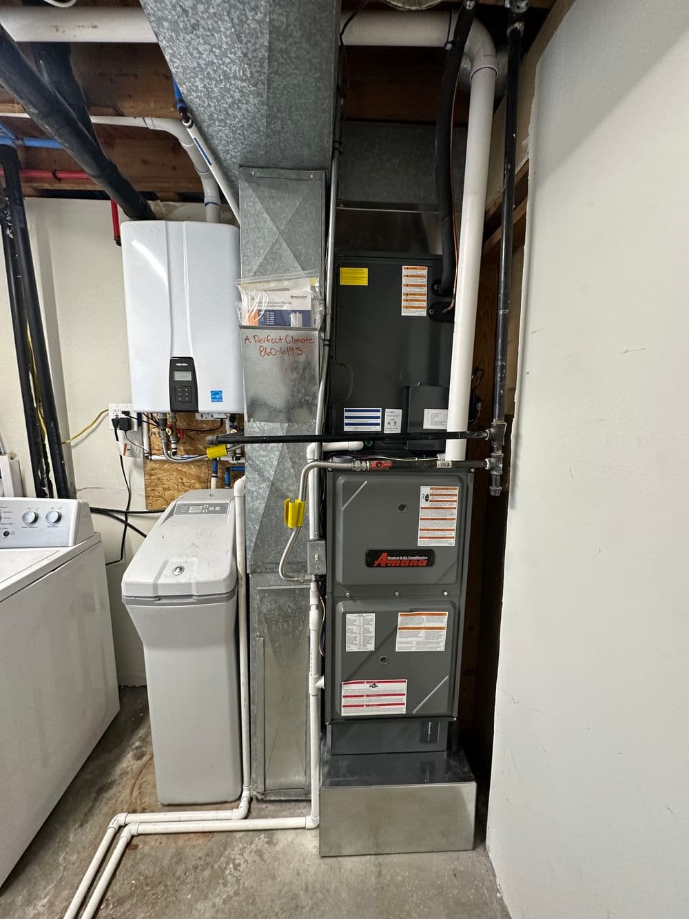 Modern HVAC system with gas furnace, water heater, and laundry appliances in basement setup.