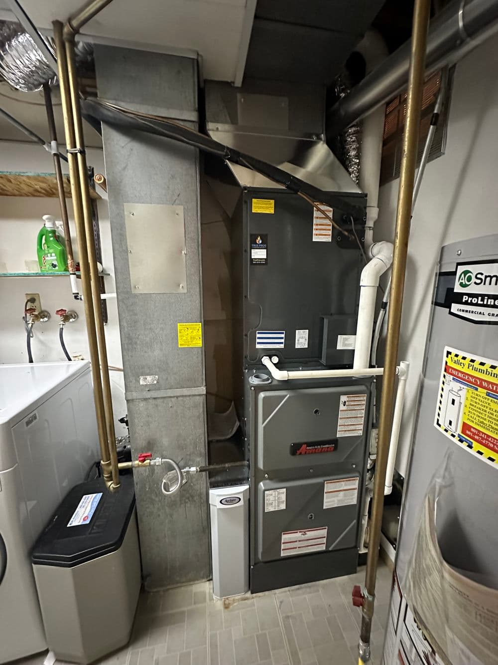 Modern gas furnace and ductwork in a basement utility room with laundry appliances nearby.