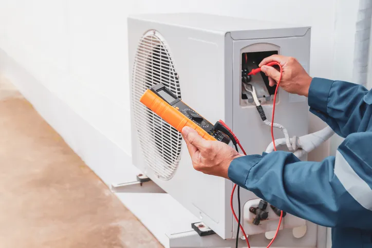 HVAC Service In West Jordan, UT 1 Technician using multimeter on outdoor HVAC unit.