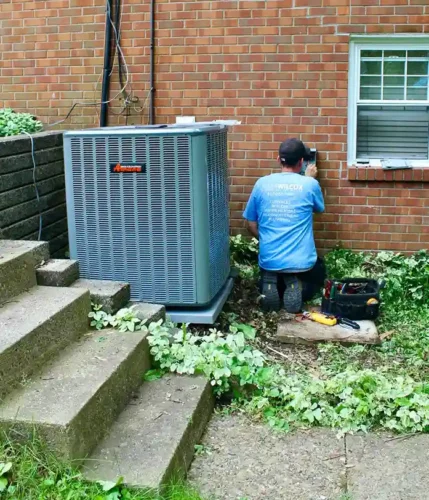 A HVAC technician repairing an AC installed outside of a home